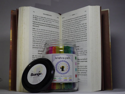 Ekanga Krishnapath Gita Jar placed in front of an open Bhagavad Gita book, showing the colorful Gita jar slips and black Ekanga lid, presented as an emotional wellness gift and Bhagavad Gita jar for peace