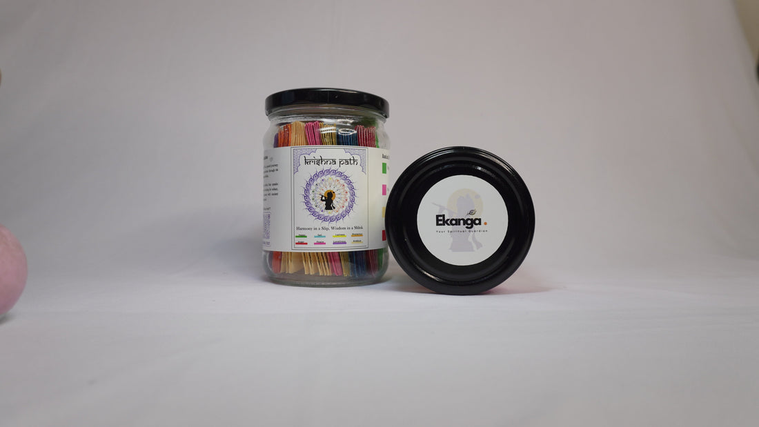 Ekanga Krishnapath Bhagwat Gita Jar with open glass jar of colorful Bhagavad Gita shloka slips, Krishnapath booklet and black lid arranged flatlay for spiritual wellness and gifting.